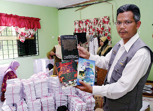 JAIM serbu markaz Syiah - Rahimin Bani menunjukkan tiga buah buku yang telah diharamkan KDN serta risalah yang dikatakan mempunyai fahaman Syiah di sebuah rumah di Taman Paya Dalam, Melaka, semalam.. [UTUSAN]